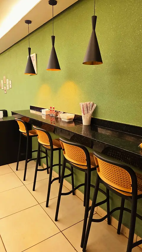 Balcão de granito com banquetas de palhinha e pendentes pretos